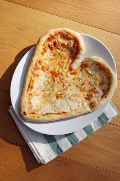 istock Heart shaped italian Pizza on table 1300464412