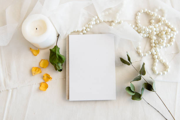 istock Layout scene of a stationery layout. An empty vertical greeting card, a string of pearls and dried flowers isolated on a white table background. Top view blank for invitation 1300467322