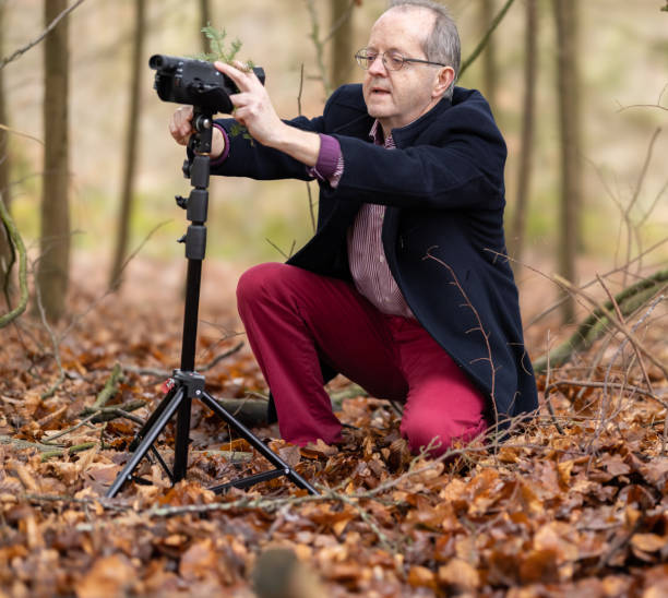 istock Positioning his camera, a middle aged man in forest is vlogging about nature, ferns and environmental conservation for youtube or social media educational channels 1300469873
