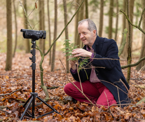 istock Middle aged man in forest vlogging about nature, ferns and environmental conservation for youtube or social media educational channels 1300469899