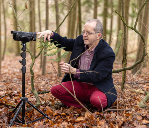 istock Middle aged man in forest vlogging about nature, ferns and environmental conservation for youtube or social media educational channels 1300469904