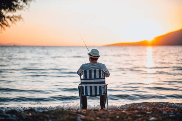 Young Man Fishing at the Beach at Sunset