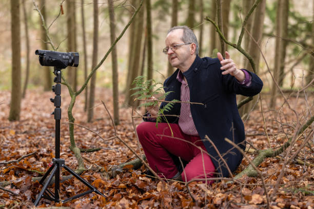 istock Middle aged man in forest vlogging about nature, ferns and environmental conservation for youtube or social media educational channels 1300469928