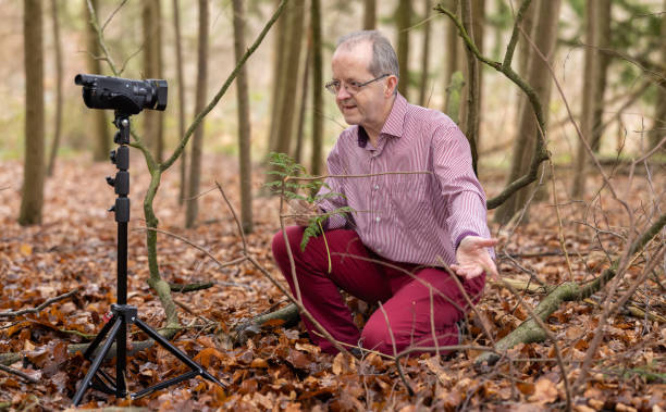 istock Middle aged man in forest vlogging about nature, ferns and environmental conservation for youtube or social media educational channels 1300469971