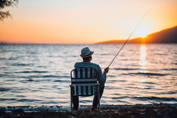 Young Man Fishing at the Beach at Sunset