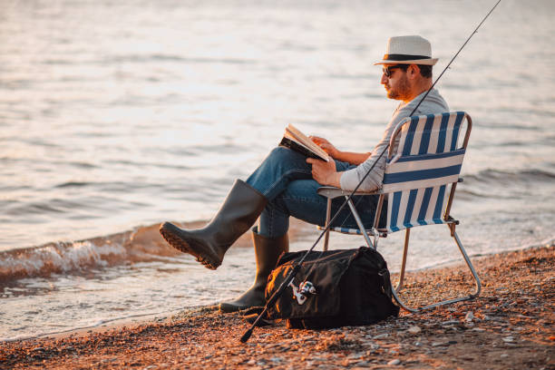 istock Young Man Reading a Book on the Beach 1300471074