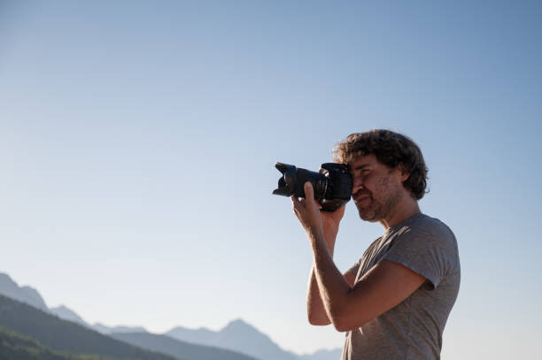 istock Young man taking photos with professional dslr camera 1300471096