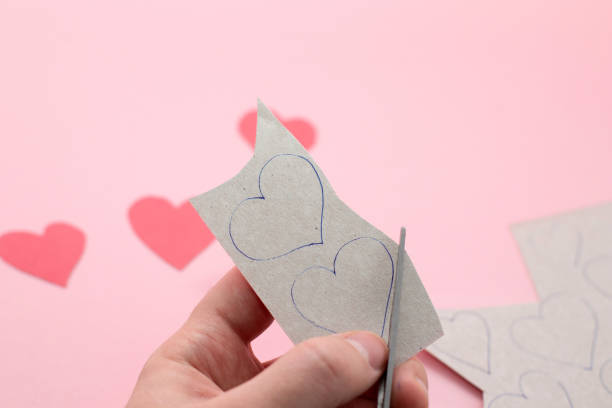 istock Hands making red Valentine card with heart and on the pink background. Step by step instructions DIY. 1300473889