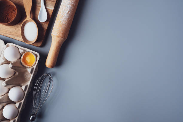 istock Different ingredients and kitchen utensils for making cookies or cupcakes, flat lay, copyspace. Eggs, rolling pin, whisk, flour, cookie molds, layout on a gray background. The concept of home baking 1300473903