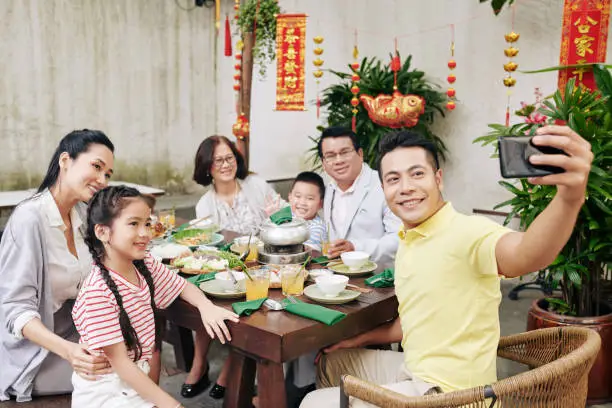 Happy middle-aged Vietnamese man taking selfie with his big family at Lunar New Year celebration