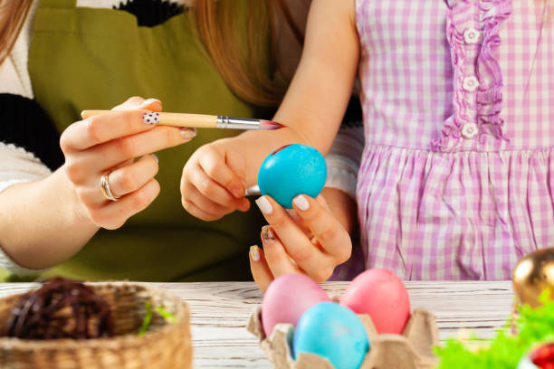 istock Mother and daughter coloring eggs for Easter 1300477033