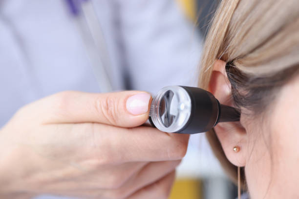 Otorhinolaryngologist looking at patients ear using an otoscope closeup Otorhinolaryngologist looking at patients ear using an otoscope closeup. Diagnosis and treatment of otitis media concept audiologist stock pictures, royalty-free photos & images