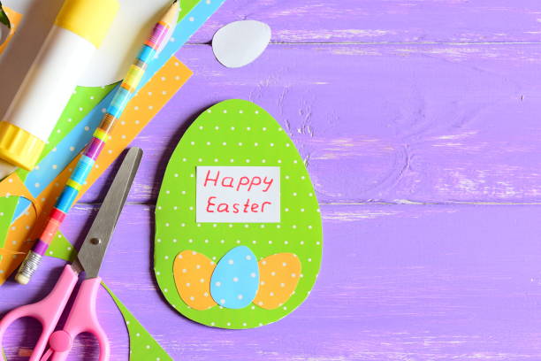 istock Happy Easter greeting card diy, craft tools and materials on purple wooden background with copy space for text. Cute greeting card made in egg form with wishes Happy Easter. Bright Easter craft background 1300480477