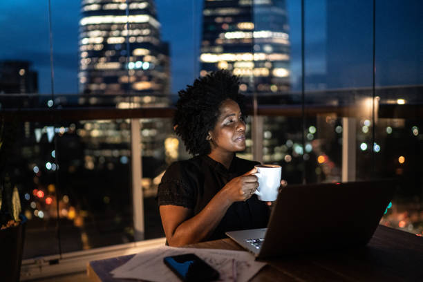 istock Woman working at home at night drinking coffee and looking away 1300481682