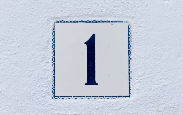 istock White ceramic square tile with blue number 1 on a white facade 1300481894