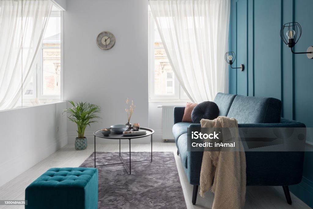 Small living room with glass wall Small living room with blue couch, ottoman and simple coffee table and with glass wall and windows with white curtains Studio Apartment Stock Photo