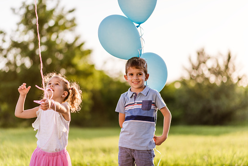 Beautiful children with balloons enjoying nature on a sunset.