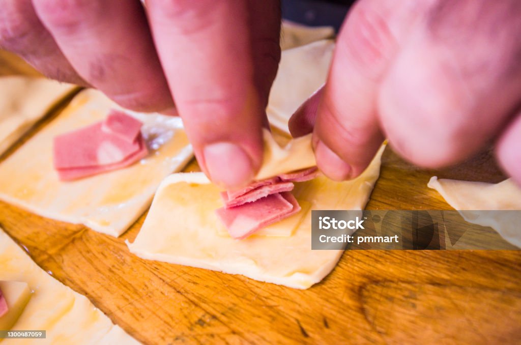 preparation of pretzels with cheese and mortadella cooked in the oven preparation of home-made savory snacks with puff pastry, mortadella, cheese and egg, cooked in the oven Adult Stock Photo
