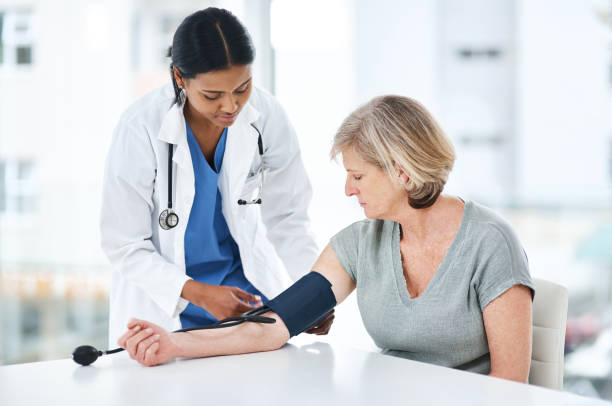 Don't leave it before it's too late Shot of a young doctor examining a senior woman with a blood pressure gauge hypertensive photos stock pictures, royalty-free photos & images
