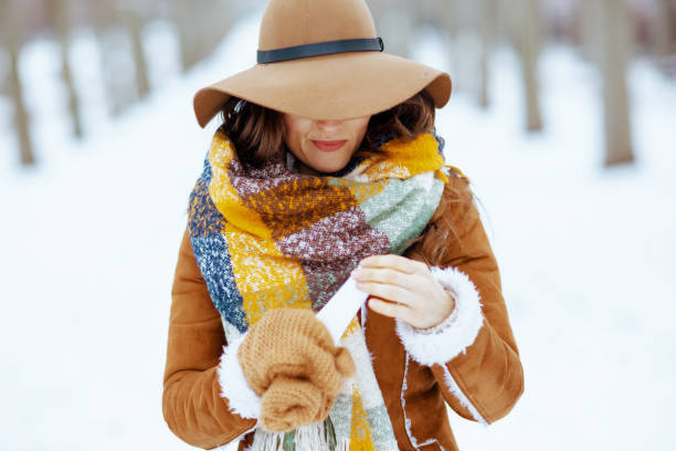istock smiling woman using cream outdoors in city park in winter 1300494099