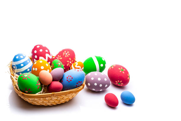 High angle view of colorful hand painted Easter eggs arranged in a wicker basket isolated on white background leaving useful copy space for text and/or logo. High resolution 42Mp studio digital capture taken with Sony A7rII and Sony FE 90mm f2.8 macro G OSS lens