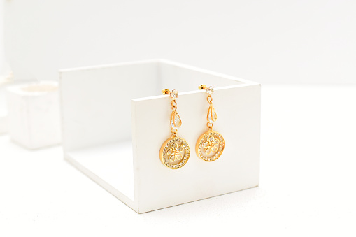 Gold earrings on minimalistic background, gold jewelry