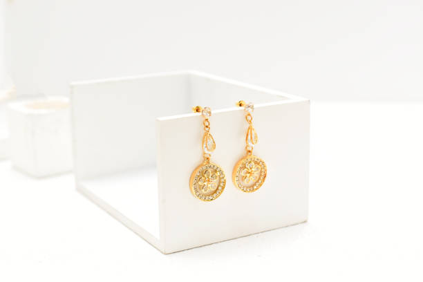 gold earrings on minimalistic background, gold jewelry - gold earring imagens e fotografias de stock