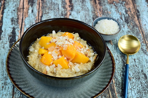Oat porridge breakfast with cubed mango and coconut chips