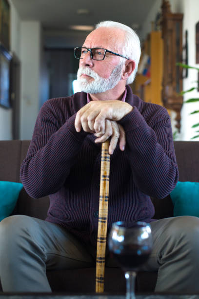 istock Senior man sitting on the sofa with walking cane 1300499391
