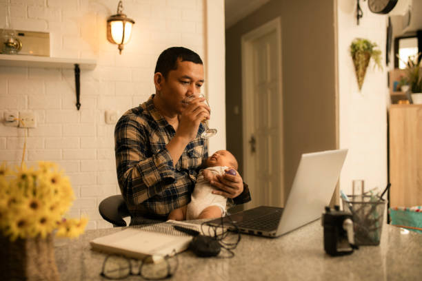 istock Working asian dad at home with  holding his cute baby 1300500594