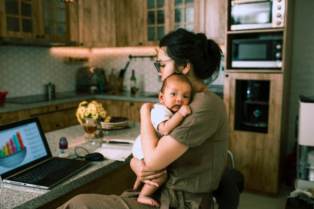 trabajando madre asiática en casa con la celebración de su bebé lindo - working mother working mother balance fotografías e imágenes de stock