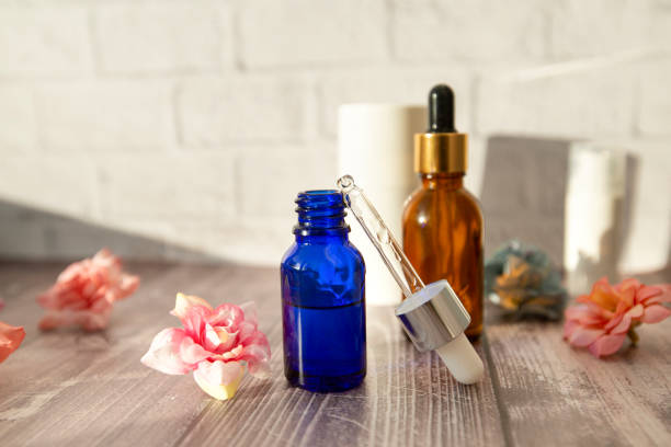 bottles and a pipette with hyaluronic serum for cosmetic and cosmetic procedures on a wooden background with flowers. bottles and a pipette with hyaluronic serum for cosmetic and cosmetic procedures on a wooden background with flowers. drop earring stock pictures, royalty-free photos & images