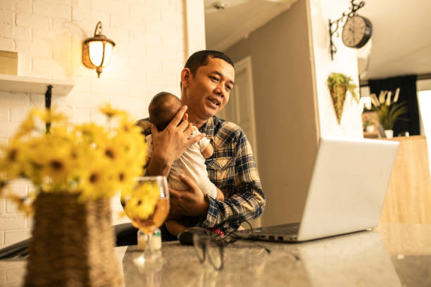 istock Working asian dad at home with  holding his cute baby 1300502474