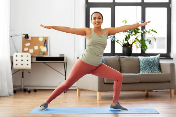 istock african woman doing yoga warrior pose at home 1300504214