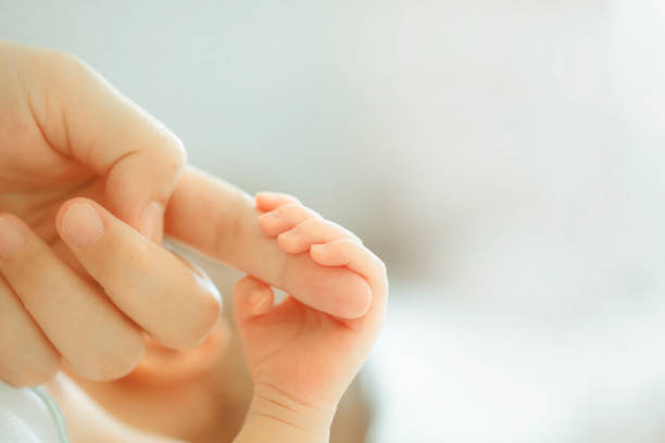 istock baby's small hand on his mother finger 1300504696