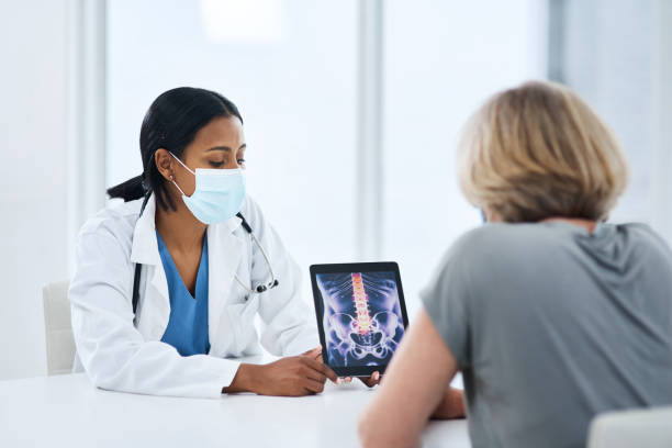 First quality patient care from diagnosis to prognosis Shot of a young doctor using a digital tablet during a consultation with a senior woman examining x ray stock pictures, royalty-free photos & images