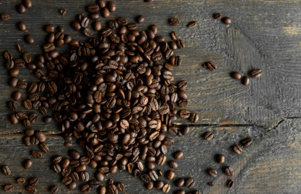 istock Roasted arabica coffee beans scattered on a wooden table. Fresh coffee beans. 1300507880