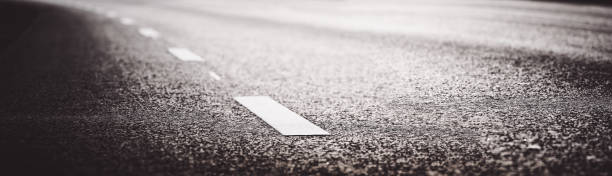 istock Black asphalt road and white dividing lines 1300508664