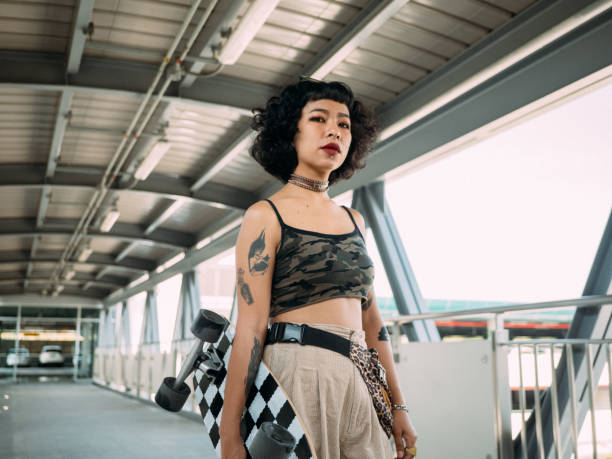 hipster azjatyckich kobiet będzie grać na deskorolce. - bangkok mass transit system zdjęcia i obrazy z banku zdjęć