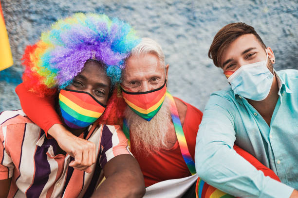 istock Multiracial gay men at lgbt pride event taking a selfie together while wearing protective face mask for coronavirus - Young and senior men 1300509079
