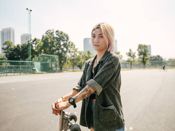 fille de l’adolescence avec le longboard dans le stationnement de planche à roulettes. - tattoo japanese culture women asian ethnicity photos et images de collection