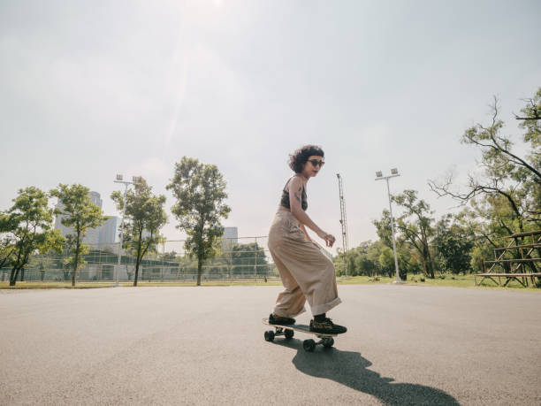 Teenage girl with skateboard in the park on a sunny day. Happy teenage girl driving skateboard at park in the city on a sunny summer day. skateboarding stock pictures, royalty-free photos & images
