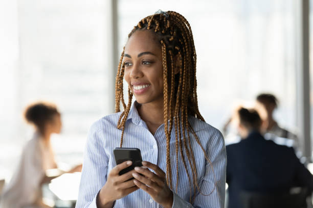 istock Smiling ethnic woman use cellphone thinking in office 1300512263