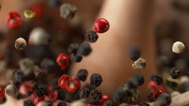 Colorful Peppercorns Crushed in Wooden Mortar in Slow Motion Macro