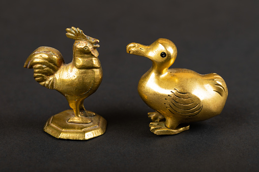 Close up picture of little gold figurine of animals on black background