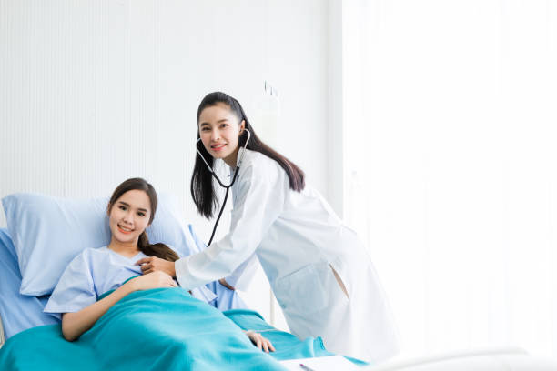 Asian young female patient on bed while doctor hands of checking examining his pulse for record the treatment results with smiley face very good symptom in hospital background. Asian young female patient on bed while doctor hands of checking examining his pulse for record the treatment results with smiley face very good symptom in hospital background. talking drum stock pictures, royalty-free photos & images