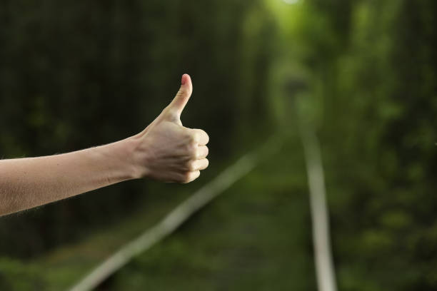 istock Like it. Thumb up with natural bokeh background of leafy green forest, hand with thumb up in the wild, gesture implying good and excellent job. gesture, like, success, people and body parts concept. 1300516607
