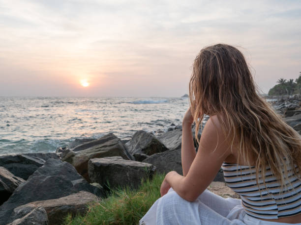 istock Woman at local beach watch sunset from coastline 1300517400
