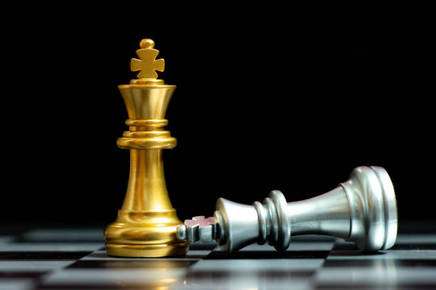 istock Gold king chess piece win over lying down silver king on black background 1300520852