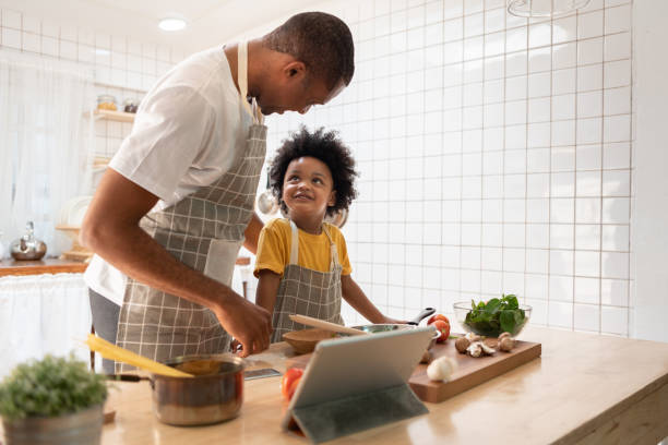istock Black African American Father and son doing online cooking with digital tablet in kitchen 1300522416